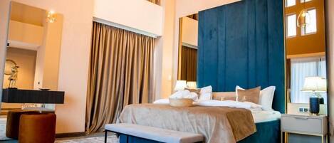 A modern hotel room with a large bed, a bench, a desk, and a chair.