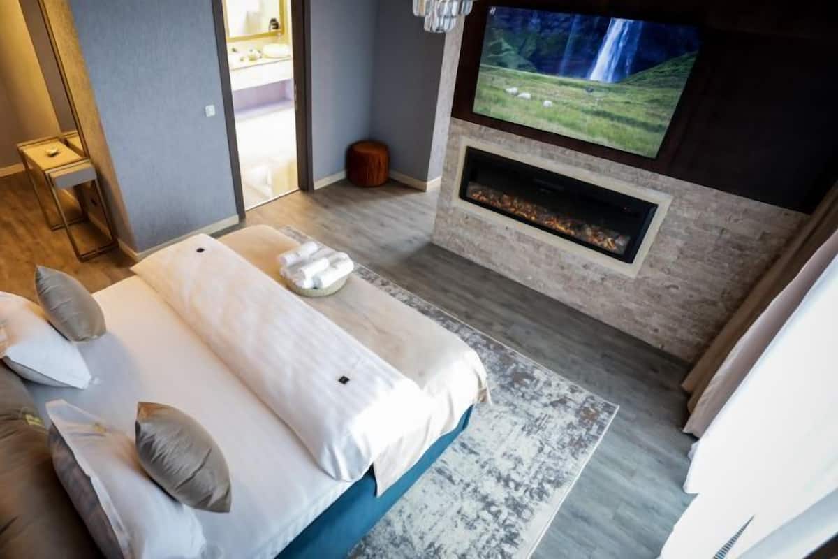 Une chambre moderne avec un grand lit, une télévision et une cheminée.