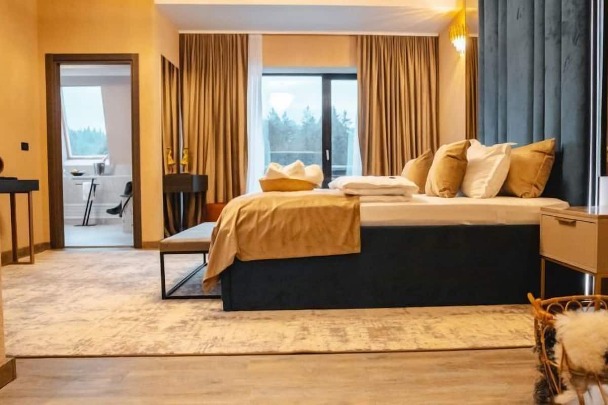 Une chambre d’hôtel moderne dotée d’un grand lit, d’un bureau et offrant une vue sur l’extérieur.
