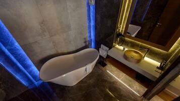 A modern bathroom with a freestanding bathtub, a round sink, and a mirror with a gold frame.