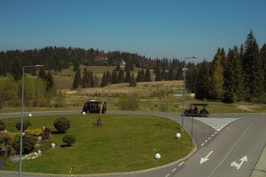 Un rond-point où l’on croise un tramway et une voiturette de golf, le tout entouré de champs verdoyants et d’arbres.