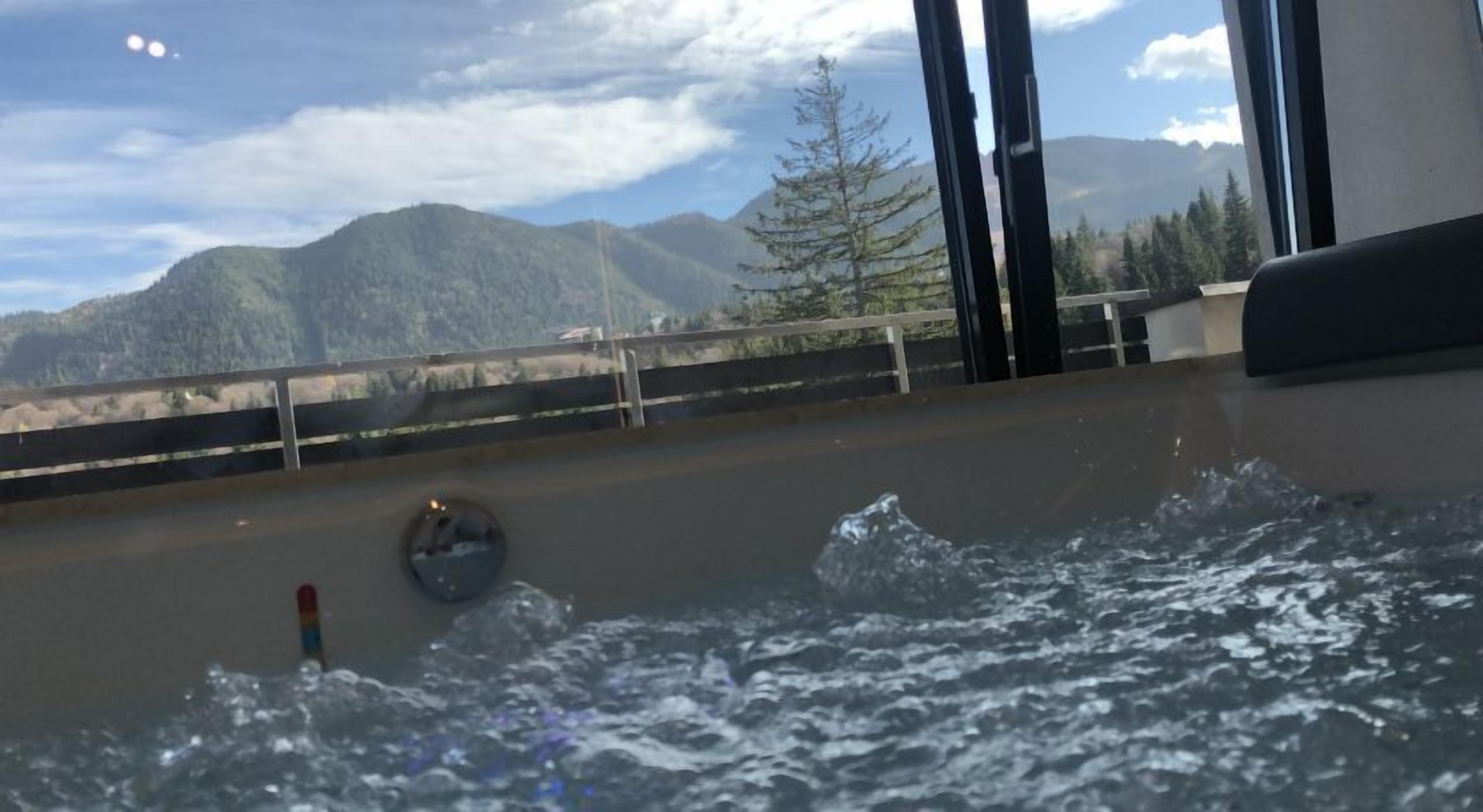 Vista pela janela, mostrando uma paisagem montanhosa, um corrimão e um elemento aquático.