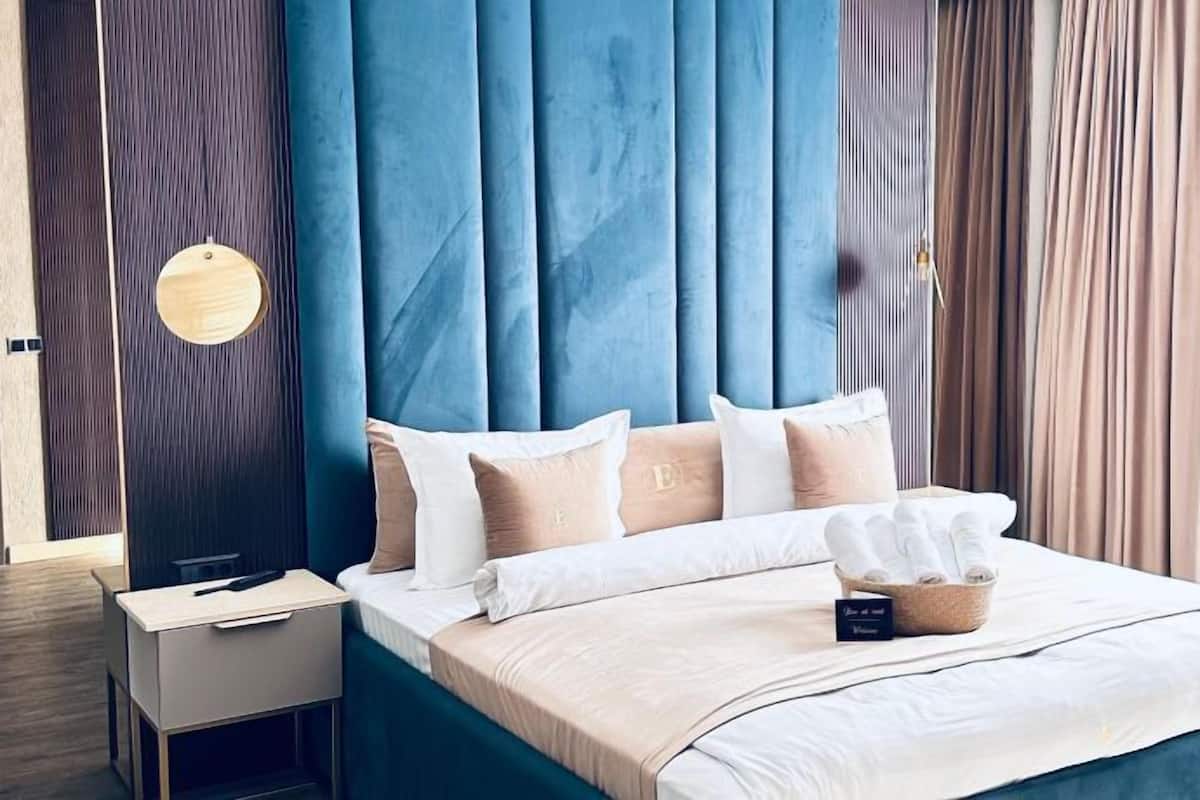 Une chambre à coucher moderne avec une tête de lit bleue, une table de chevet et un lit avec une literie blanche et une boîte à mouchoirs.