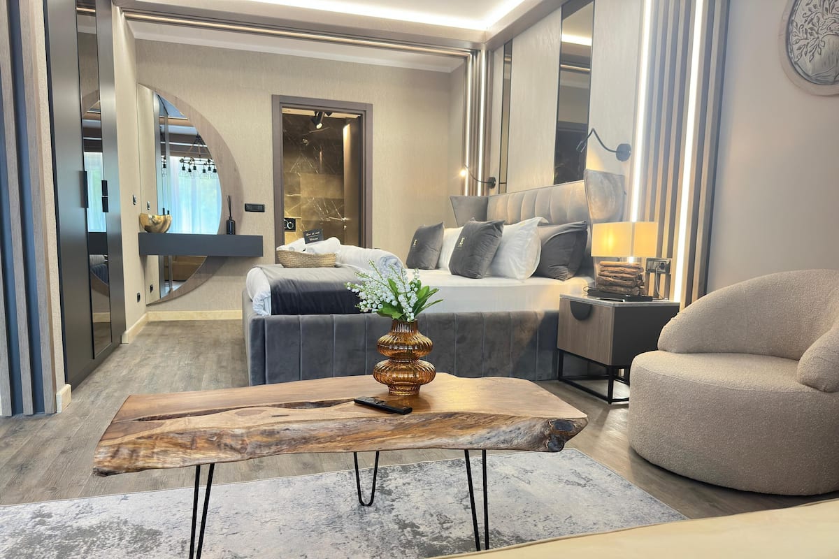 Une chambre d’hôtel moderne comprenant un lit, un coin salon avec une table basse et une table de chevet.