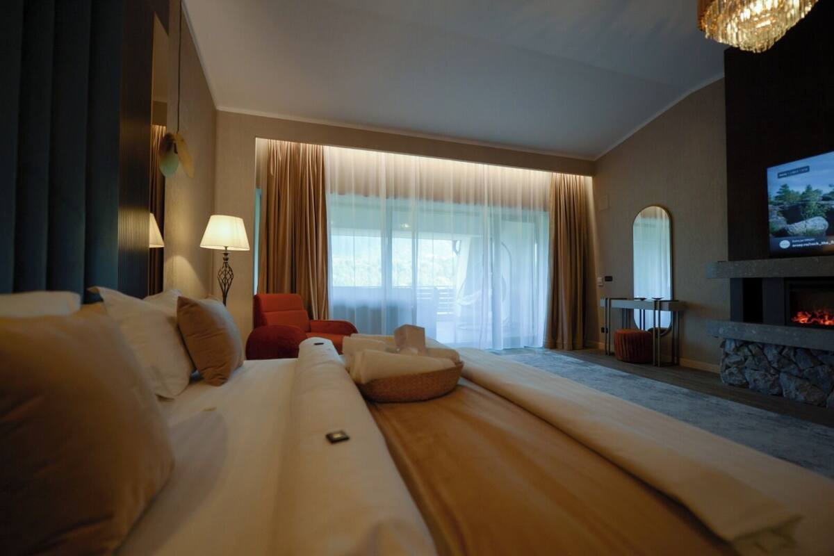 Une chambre d’hôtel avec un grand lit, un fauteuil rouge, une télévision et une cheminée.