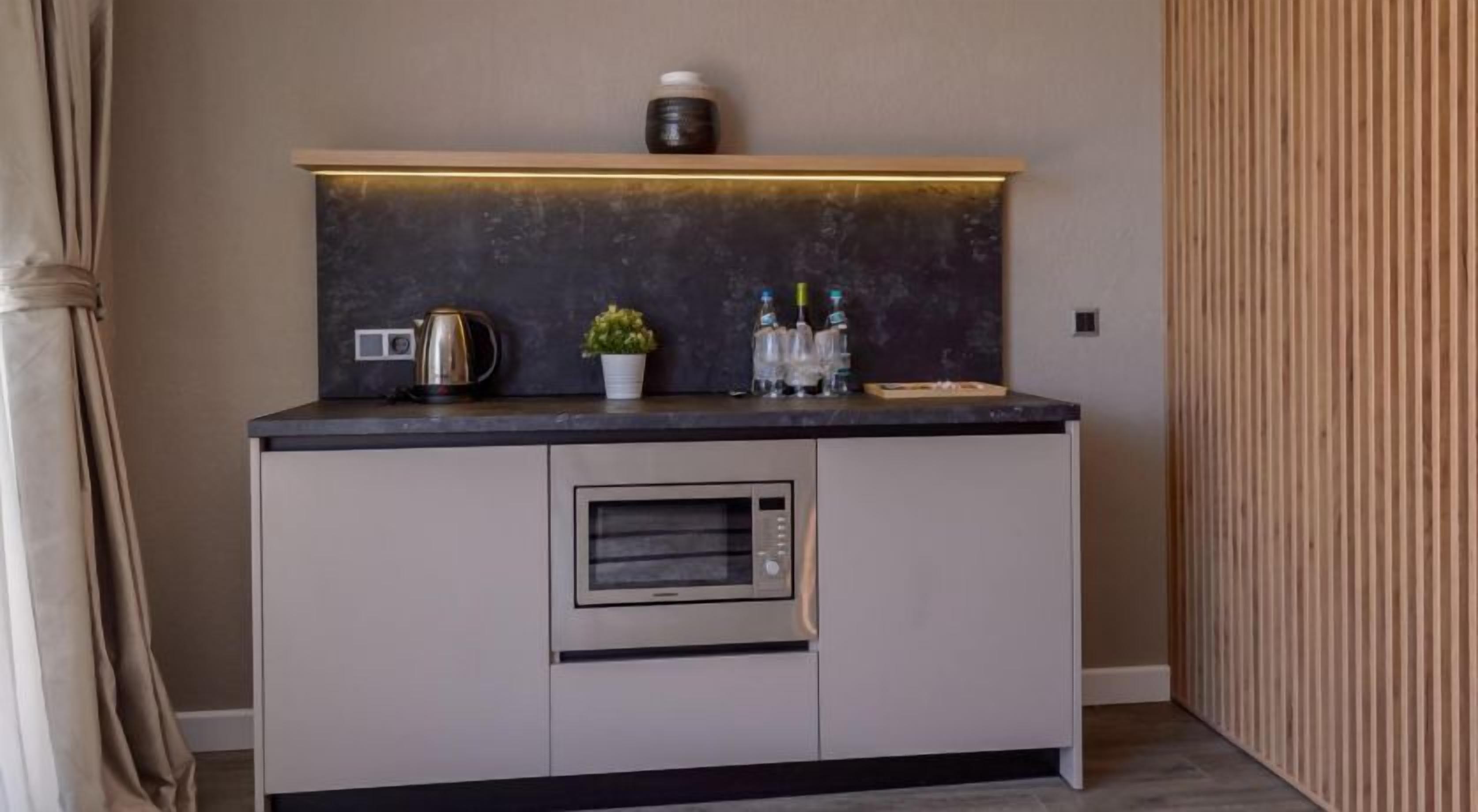 A compact kitchenette with a built-in oven, a kettle, and a small potted plant.