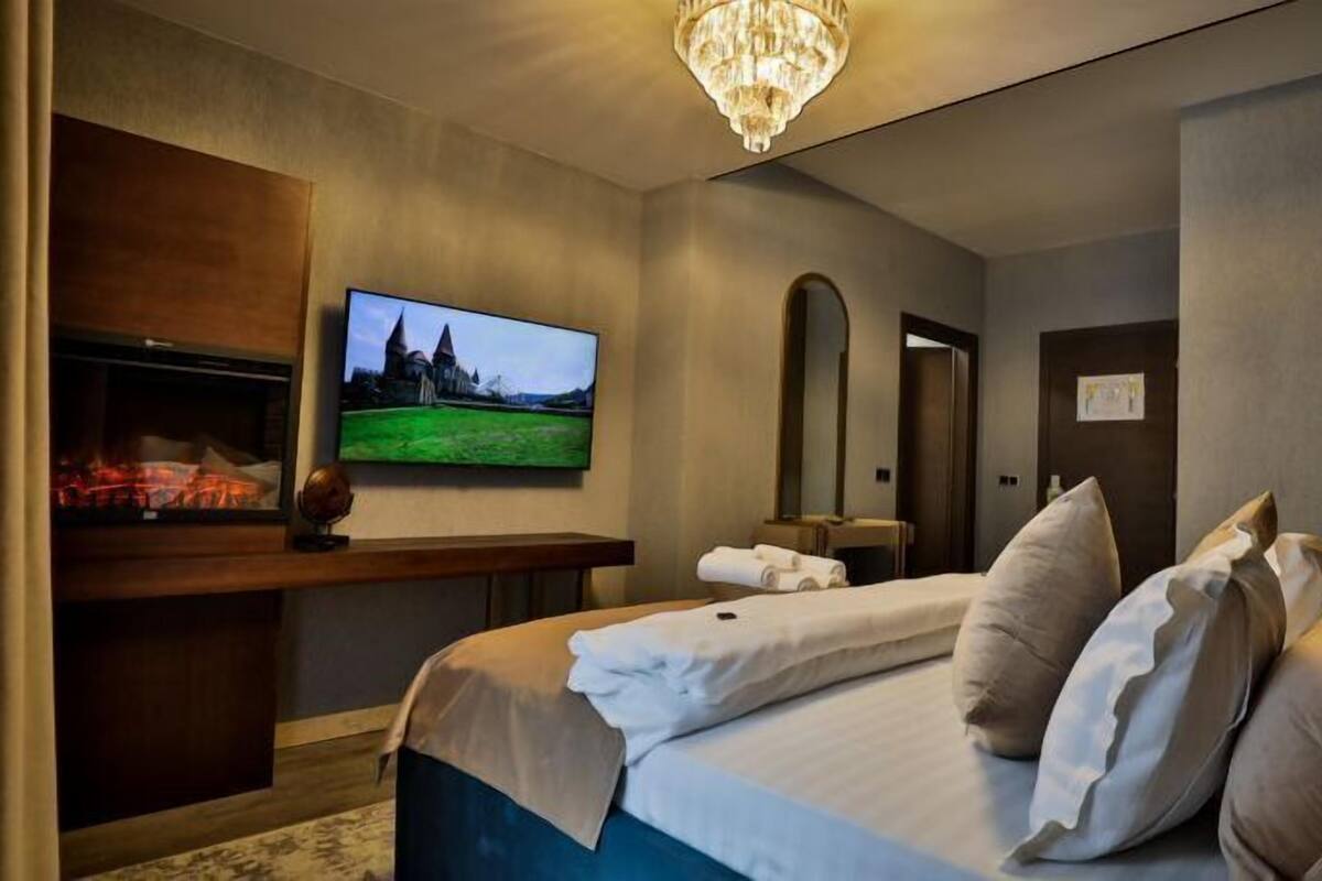 Une chambre d’hôtel avec un lit, une télévision, une cheminée et un miroir.