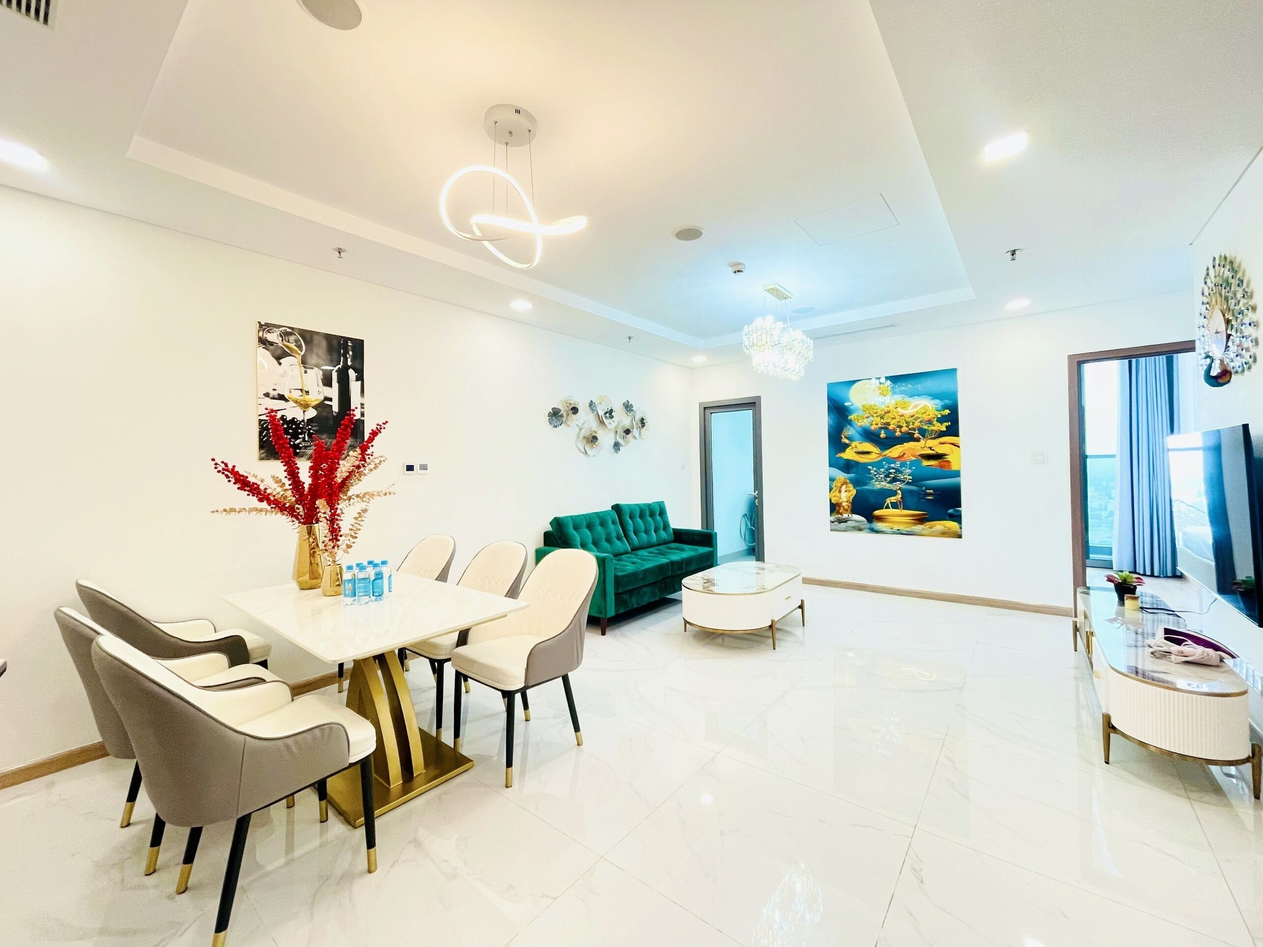 A spacious living area with a dining table, chairs, a sofa, and a TV.