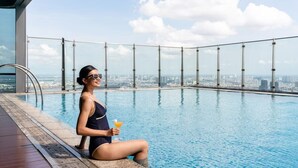 Eine Person entspannt am Pool mit Blick auf die Stadt.