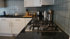 A kitchen with white cabinets, a black countertop, and a gas stove. - Lady Jane Court (Cambridge)