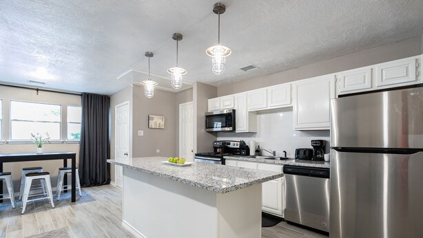 A modern kitchen with white cabinets, stainless steel appliances, and a granite countertop. - 2BR The Cardinal C! Montrose, Downtown MedCenter ⭐️⭐️⭐️⭐️⭐️ (Houston)