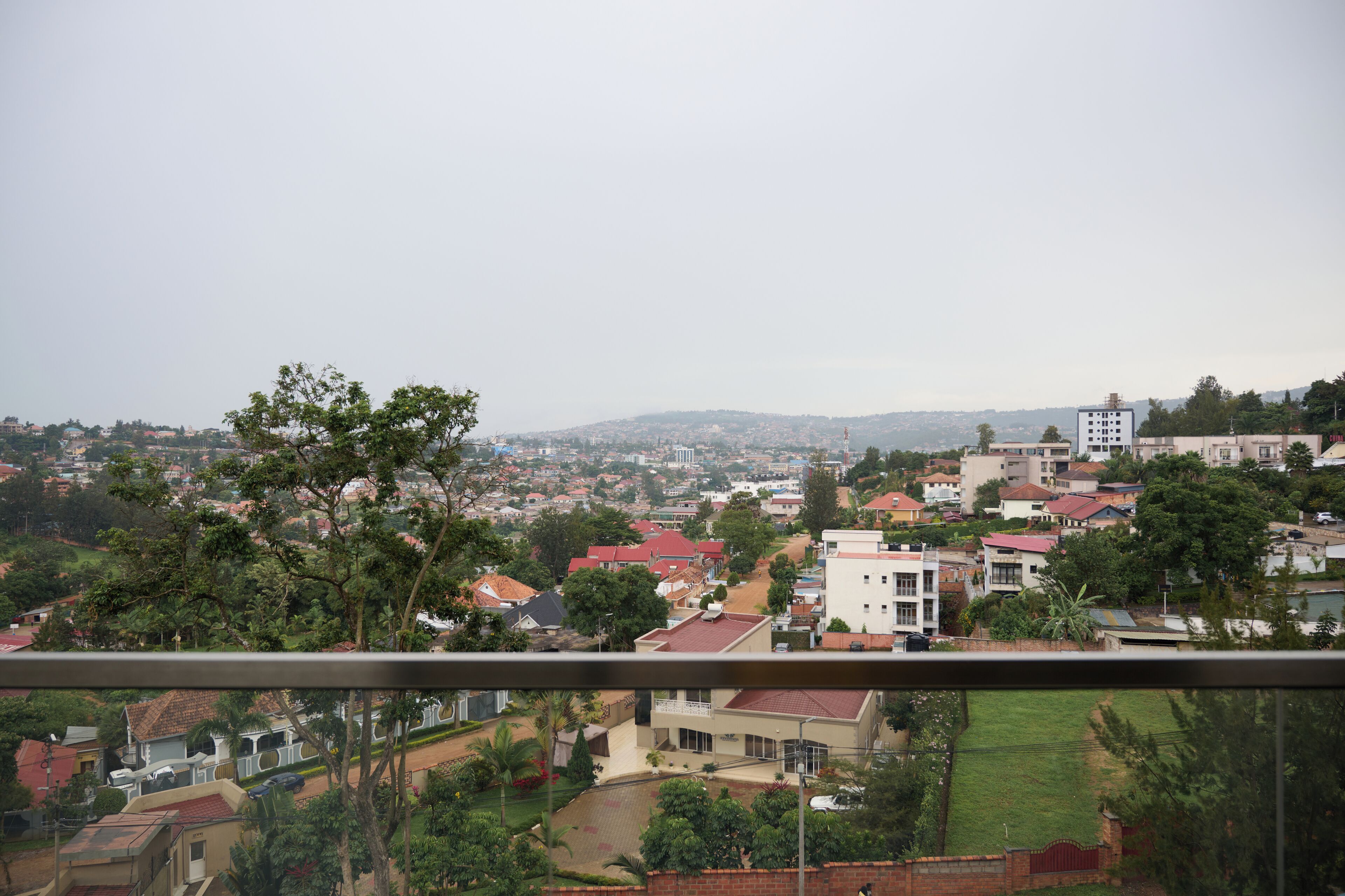 A residential area with houses, trees, and a distant view of a cityscape.