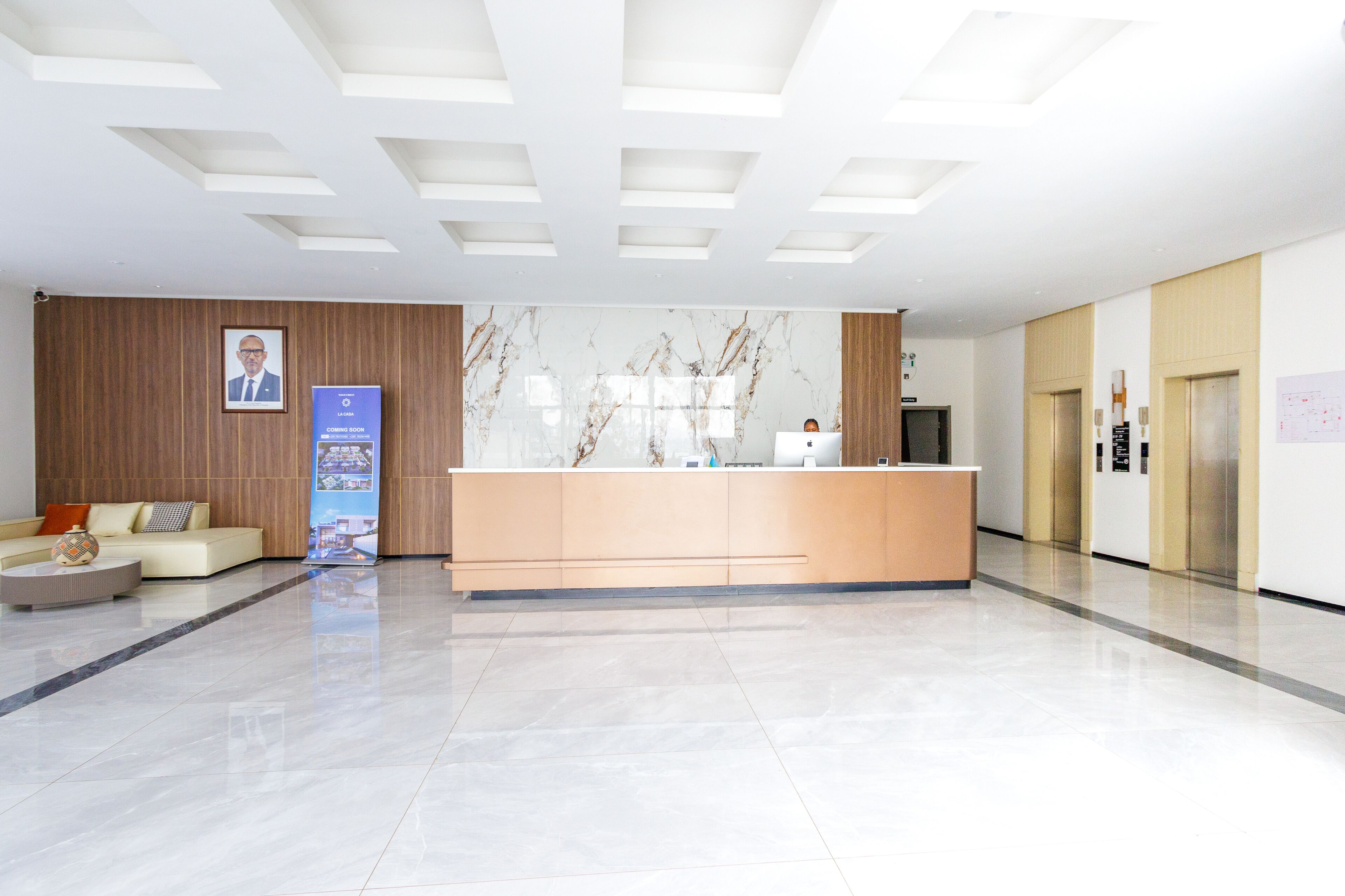 Un área de recepción moderna con una pared de mármol, un mostrador de madera, un sofá y una mesa de centro.