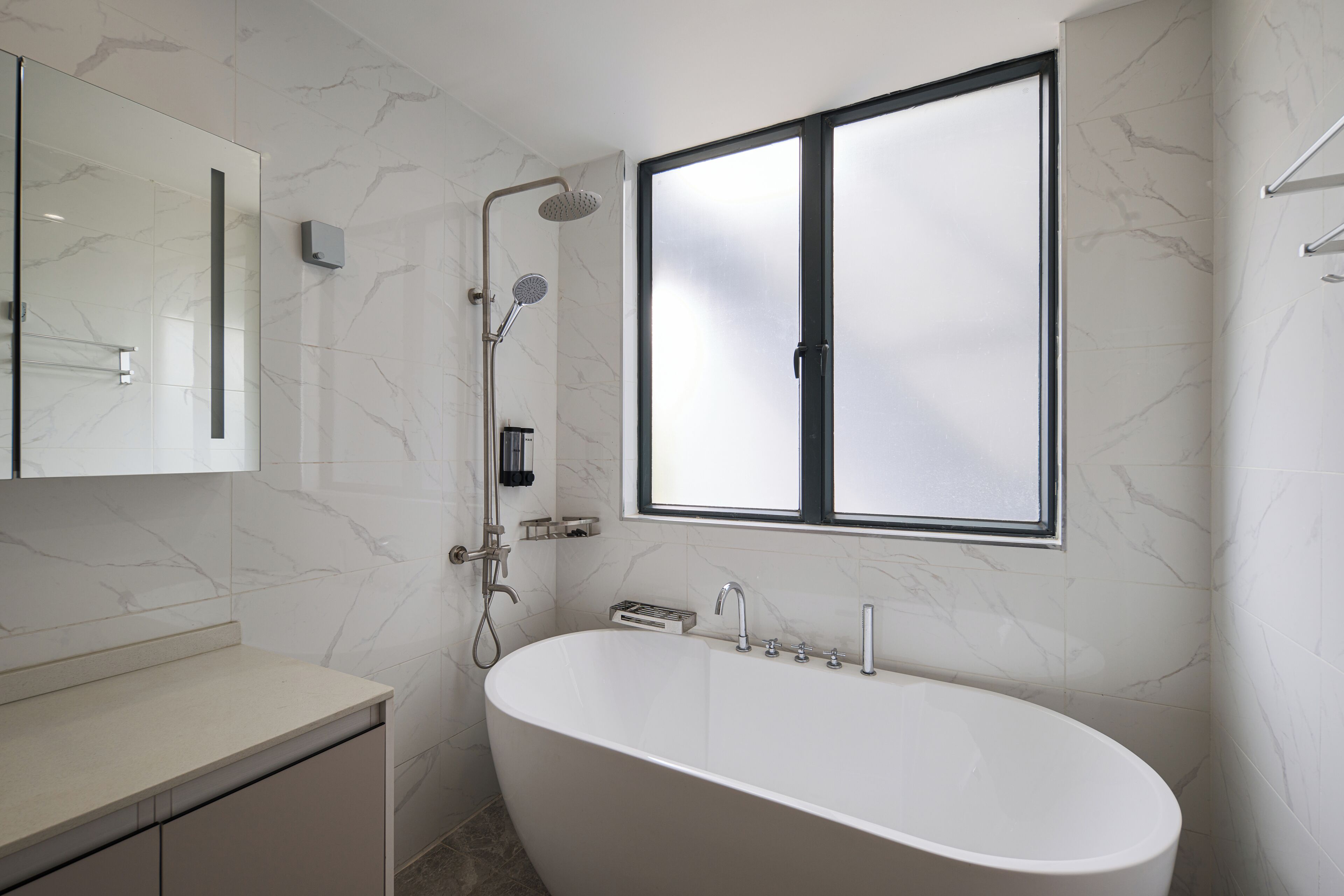 Un baño moderno con una bañera independiente, un box de ducha de vidrio y un ventanal amplio.