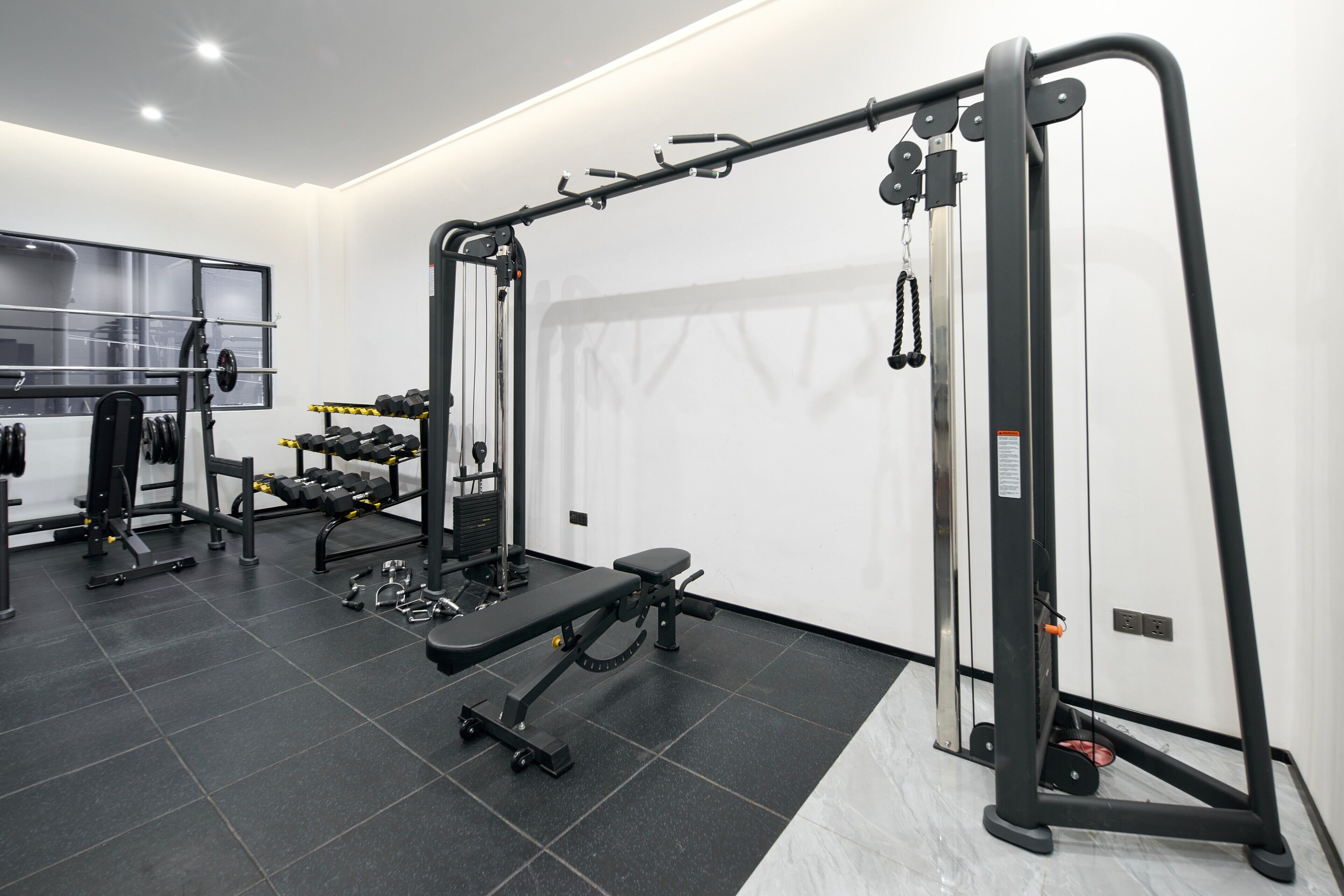 A gym with various exercise equipment, including a bench, dumbbells, and a squat rack.