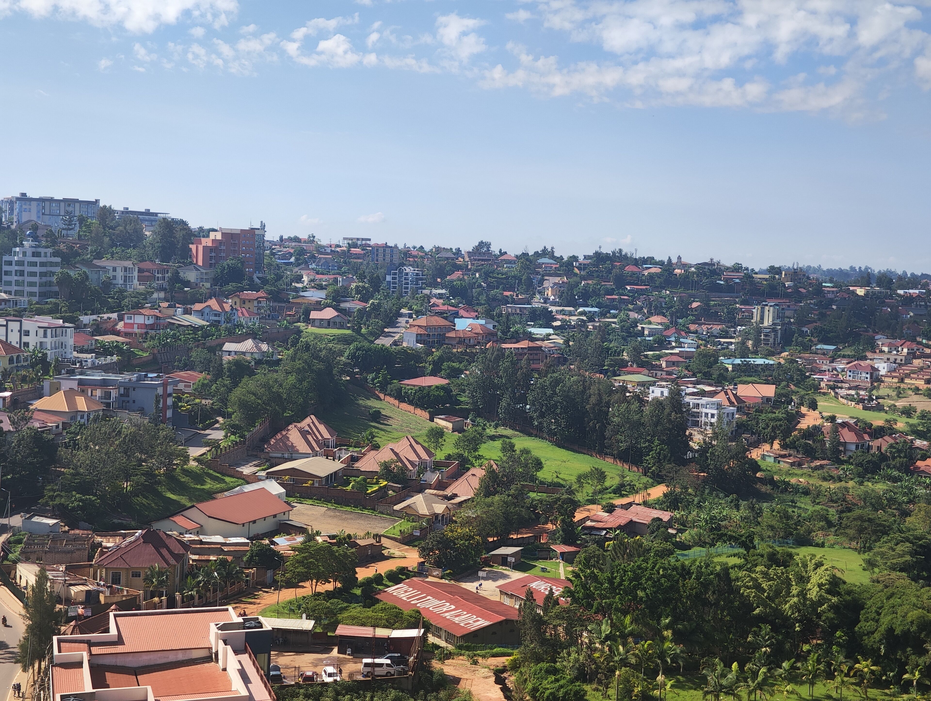 A residential area with houses, some with red roofs, and a few taller buildings in the background.