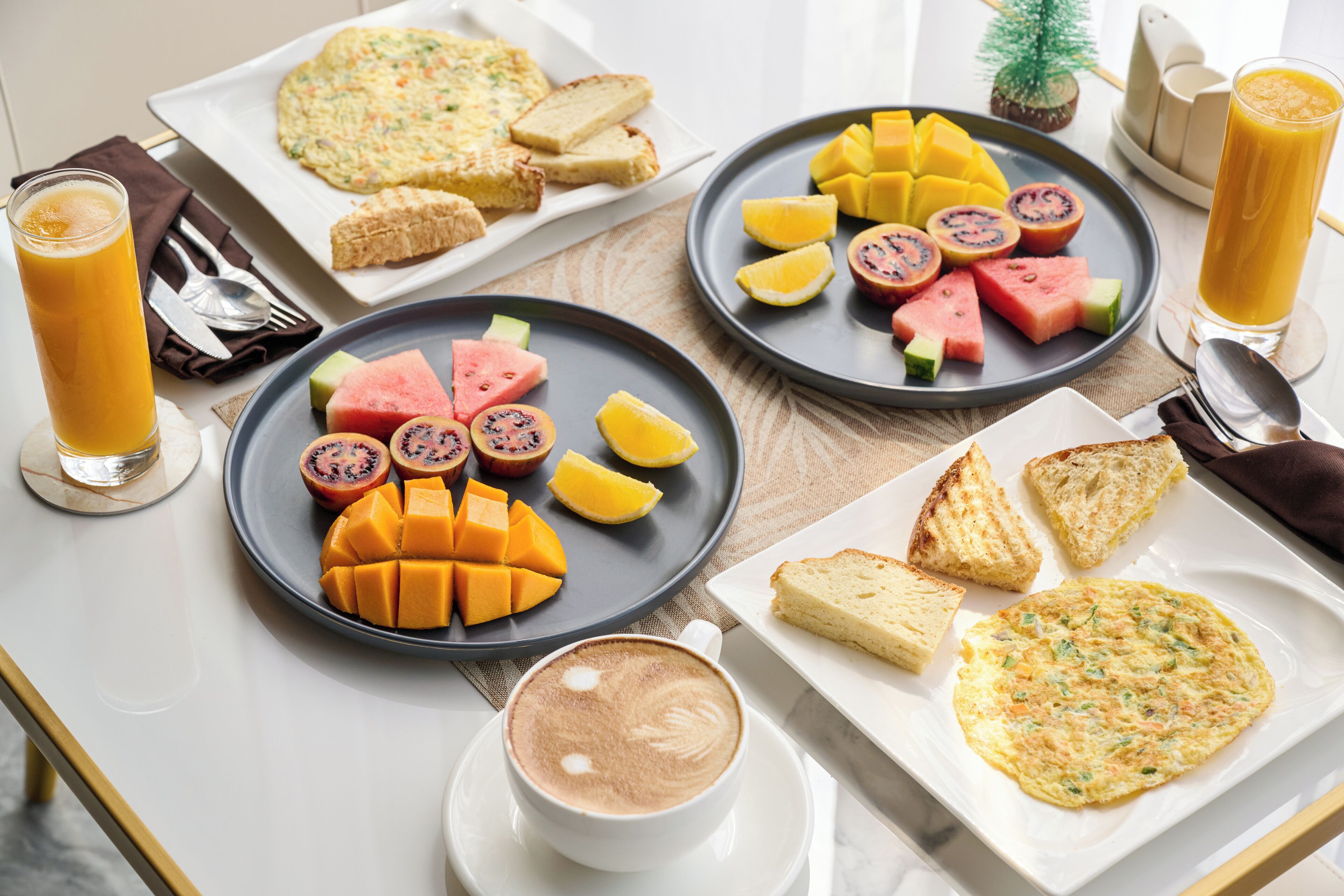 A breakfast setting with plates of fruit, toast, and a coffee cup.