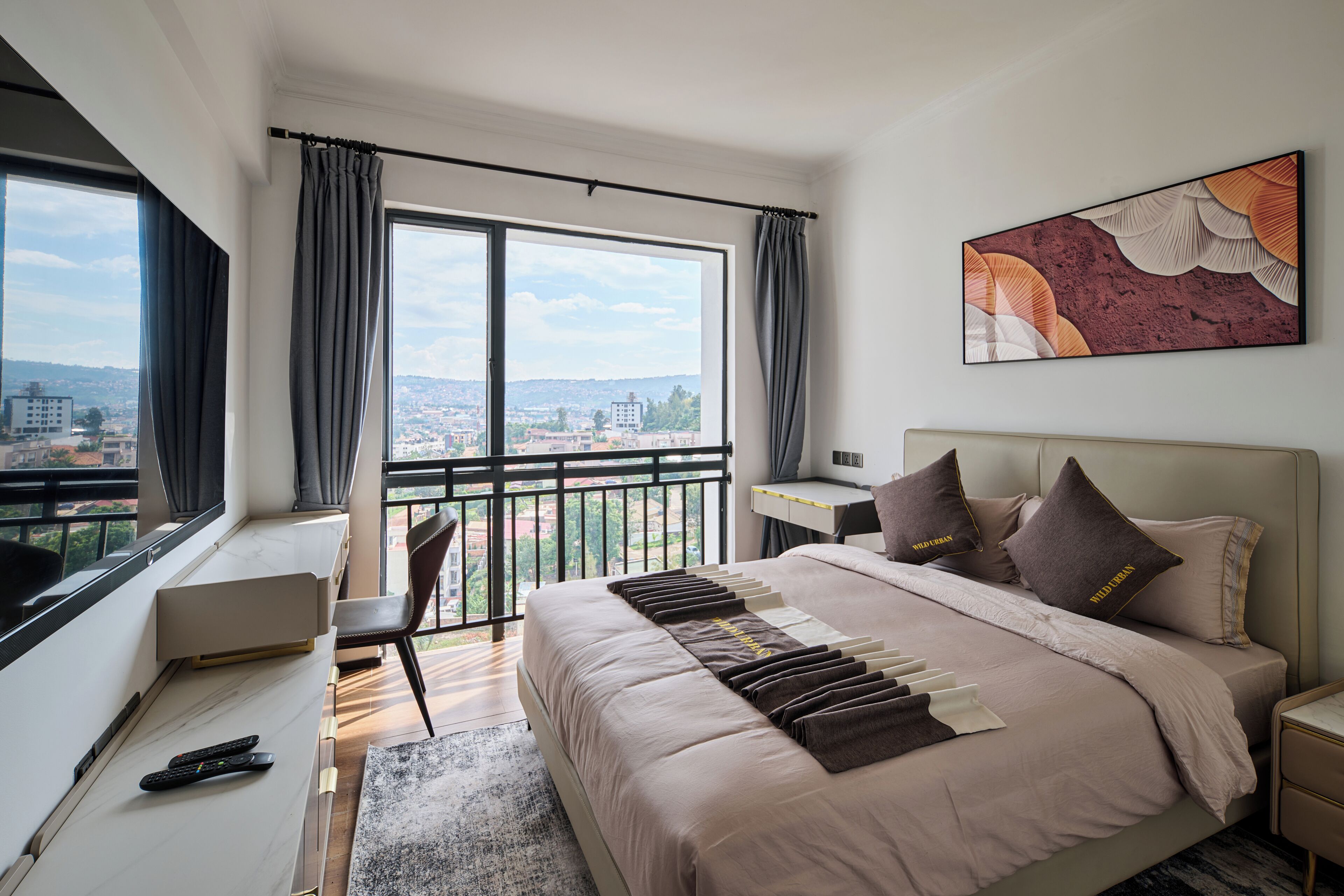 A modern hotel room with a large bed, a desk, and a view of the city.