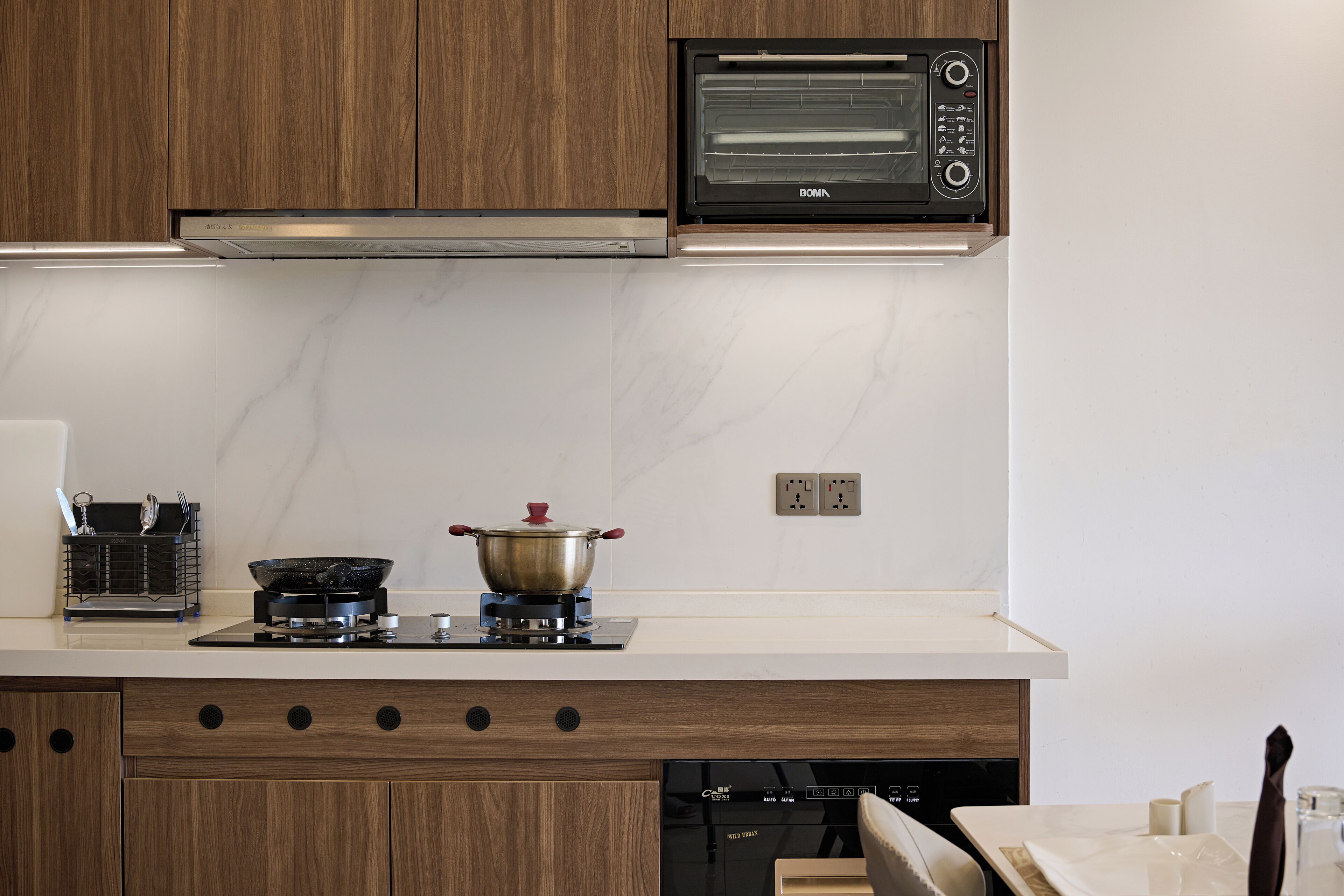 Una cocina moderna con armarios de madera, microondas integrado, estufa a gas y lavavajillas.