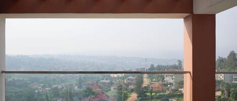 A balcony with a view of a residential area, a table, and two chairs.