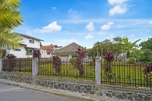 Two homes nestled among lush greenery, surrounded by a well-maintained stone wall and metal fence.