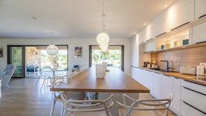 A modern kitchen with white cabinets, a wooden countertop, and a hanging light fixture. - Villa Lubama 1, Style Bergerie, Entre mer et Montagne Avec Piscine (San-Gavino-Di-Carbini)