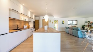 A modern kitchen with white cabinets, a wooden countertop, and a central island. - Villa Lubama 1, Style Bergerie, Entre mer et Montagne Avec Piscine (San-Gavino-Di-Carbini)