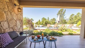 A patio with a stone wall, a sofa, two tables with breakfast items, and outdoor seating. - Villa Lubama 1, Style Bergerie, Entre mer et Montagne Avec Piscine (San-Gavino-Di-Carbini)