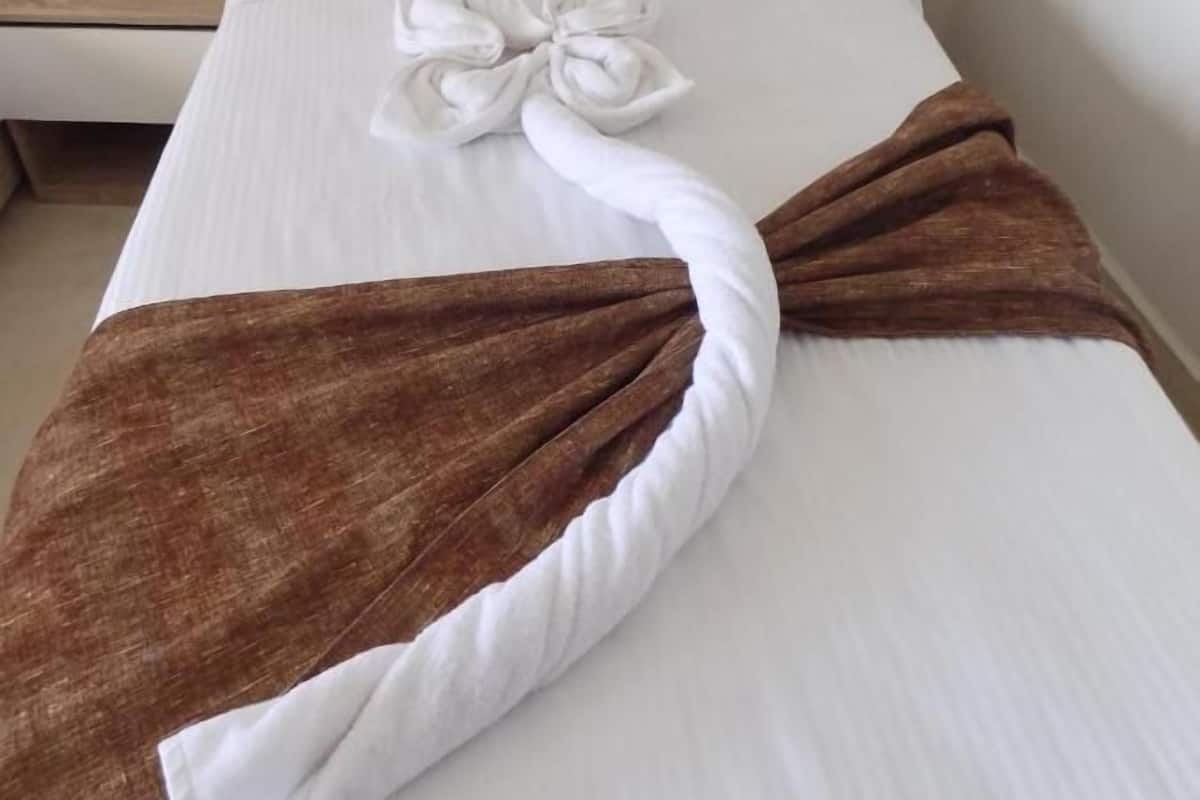 A hotel room with a neatly made bed, a wooden headboard, a bedside table with a lamp, and a phone.