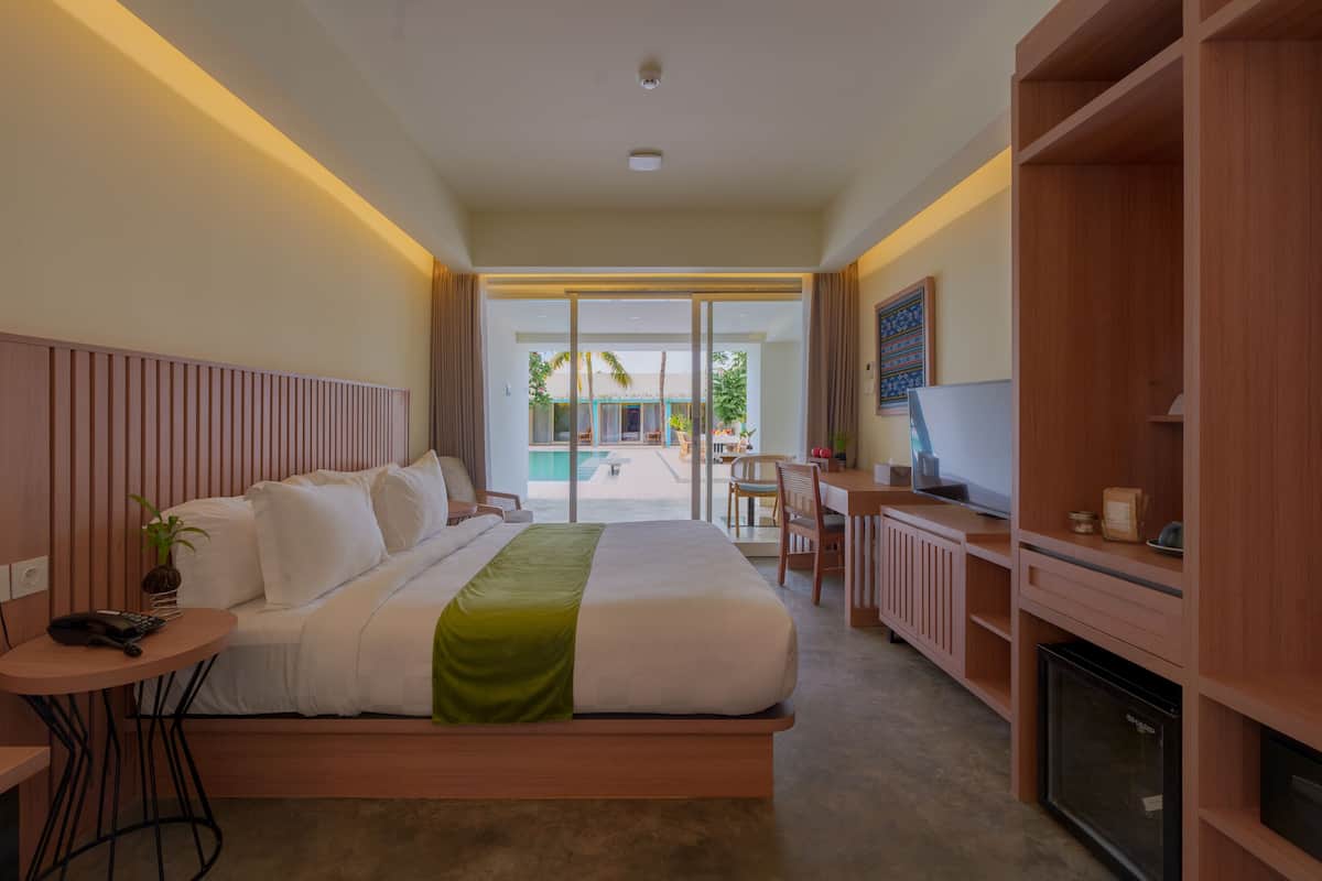 Quarto de hotel moderno com uma cama grande, uma escrivaninha, uma televisão e vista para a área da piscina externa.