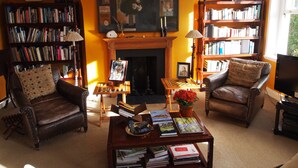 A cozy living room with leather armchairs, a fireplace, and bookshelves filled with books. - Luxury Apartment in Chelsea (London)