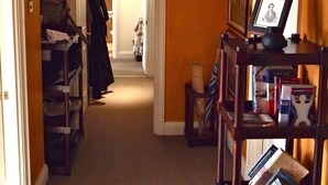 A hallway with a wooden bookshelf, a framed picture, and a door leading to another room. - Luxury Apartment in Chelsea (London)