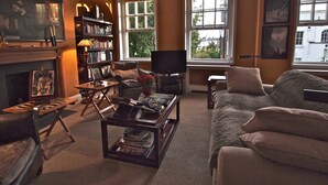 A living room with a fireplace, bookshelves, a television, and a sofa. - Luxury Apartment in Chelsea (London)