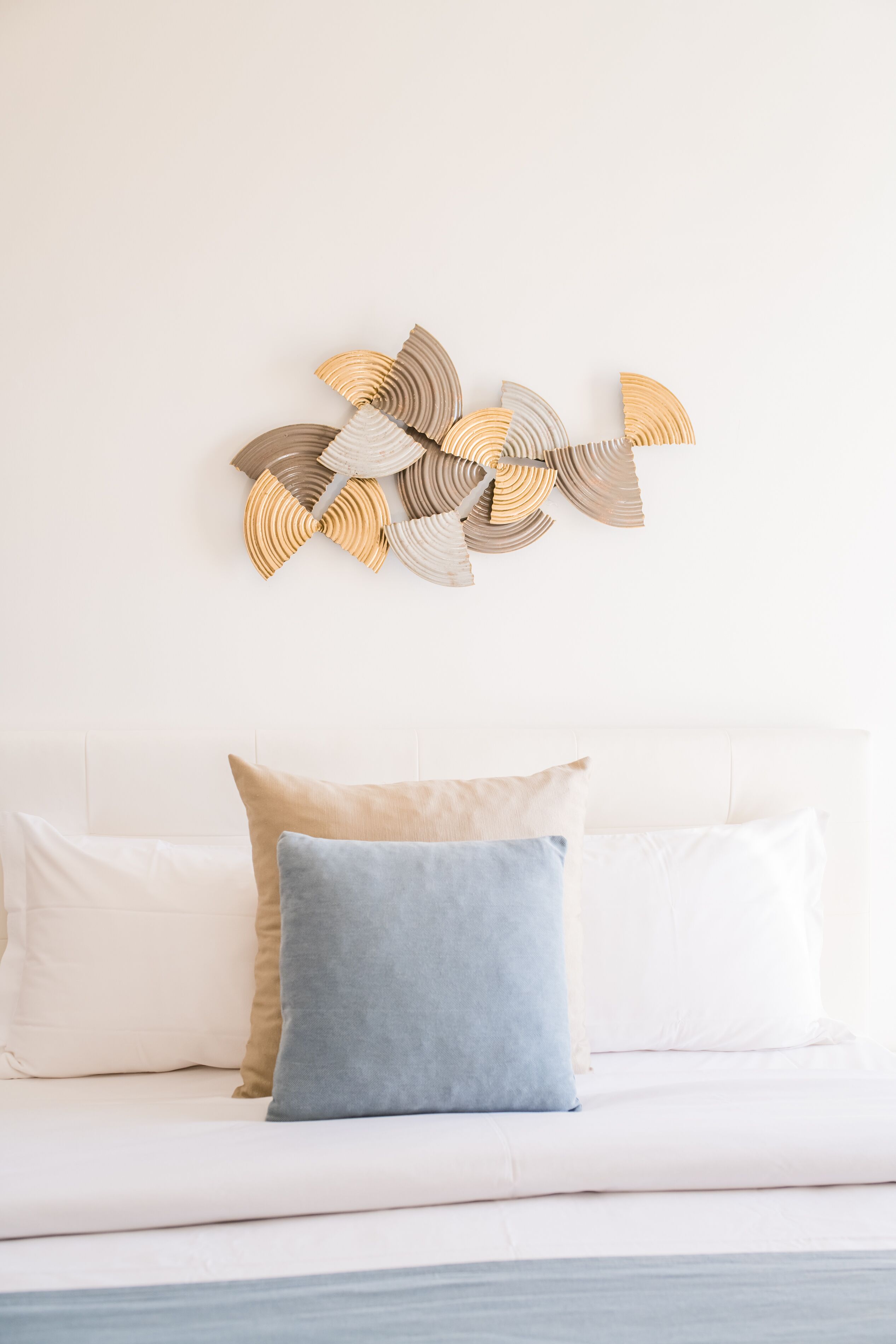 Un divano bianco con due cuscini, uno azzurro chiaro e uno beige, appoggiato su un muro bianco.