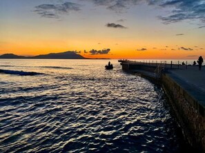 Ein Küsten-Sonnenuntergang mit einer Mole und ruhigem Wasser.
