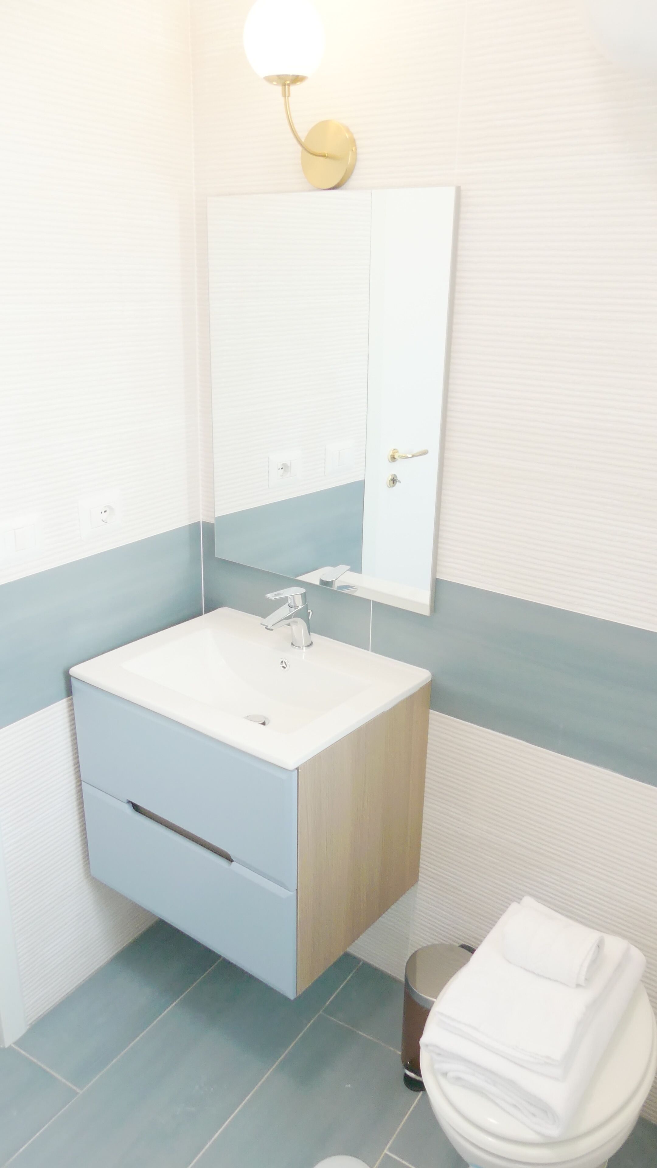 A bathroom with a white sink, a mirror, and a toilet.