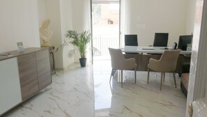 A reception area with a marble floor, a reception desk, two chairs, a potted plant, and a statue. - Naro Suites and Rooms (Bacoli)