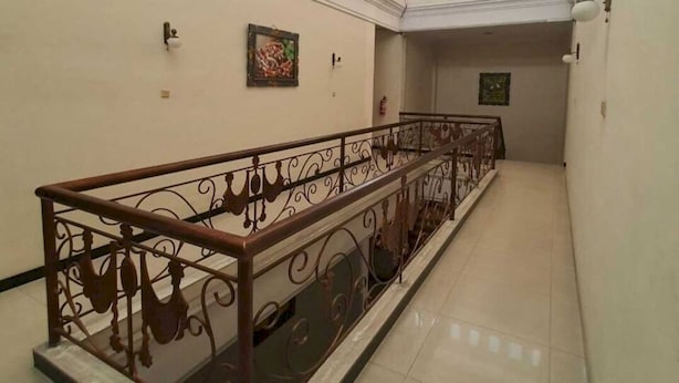 A long, narrow hallway with a decorative metal railing and tiled floor. - OYO Life 93202 Pentagon Homestay Syariah (Surabaya)