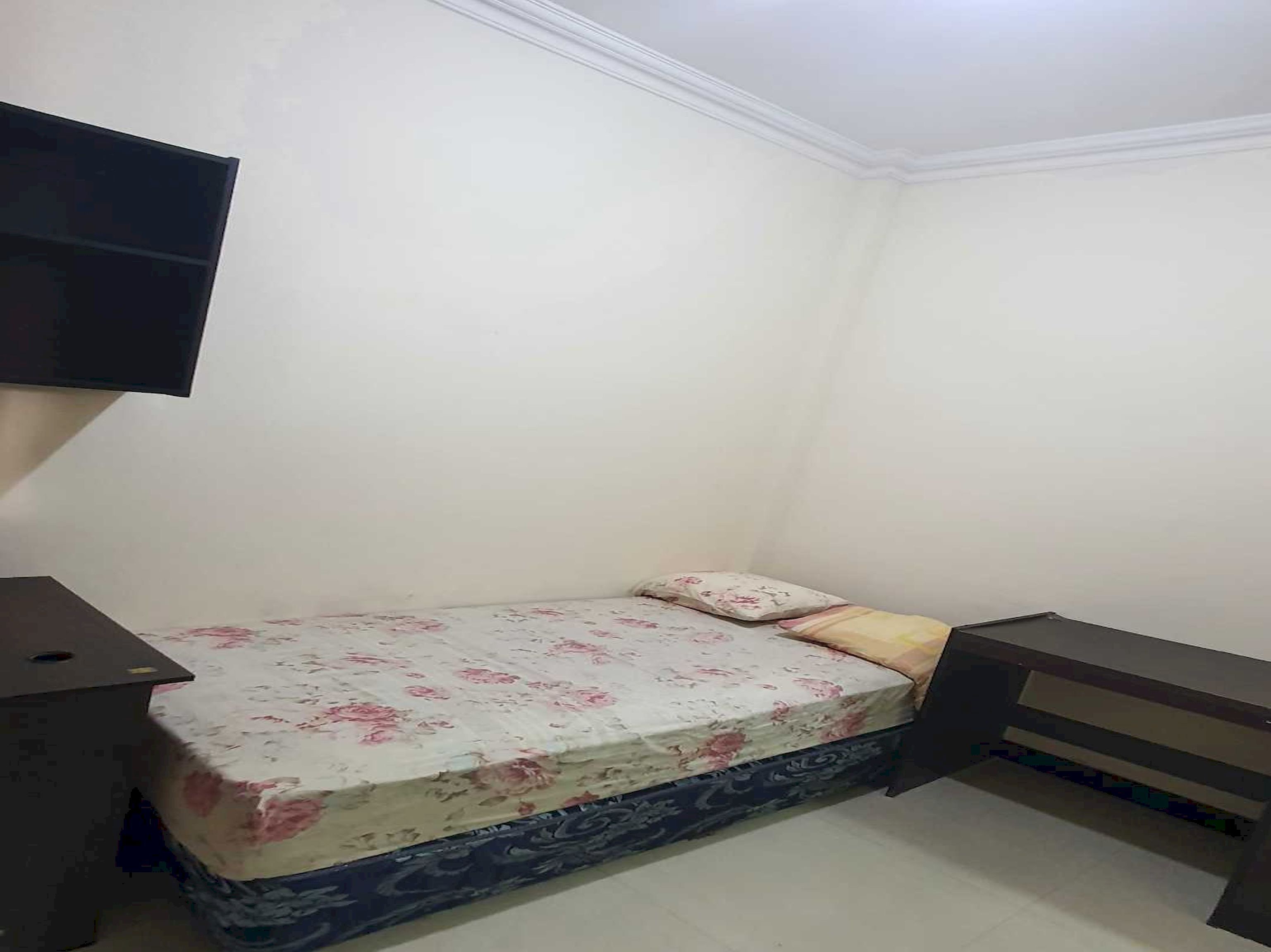 Un dormitorio pequeño y ordenado con una cama, una mesita de noche y un escritorio.