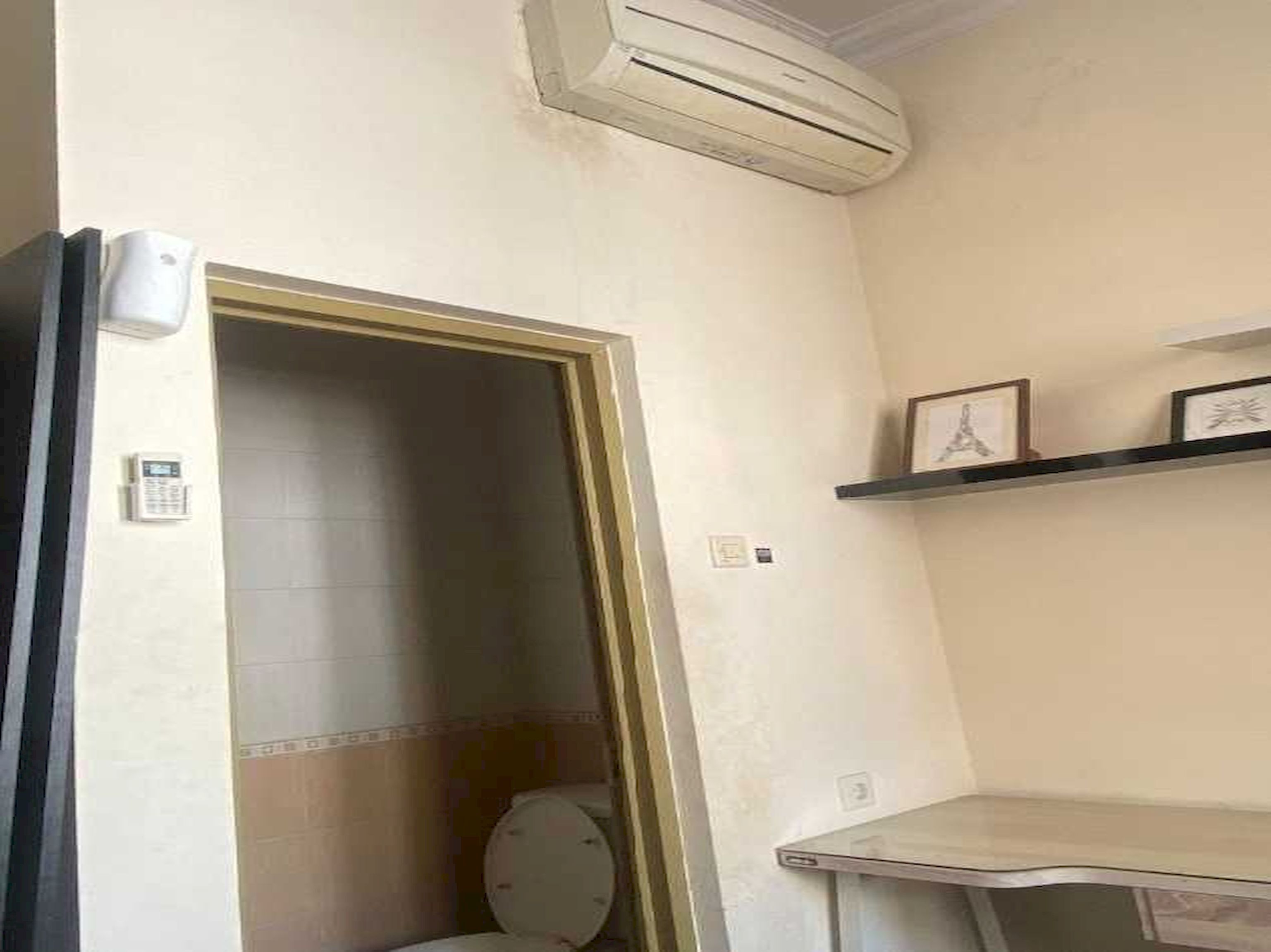 Een badkamer met een toilet, een douchegedeelte en een klein plankje met fotolijstjes.