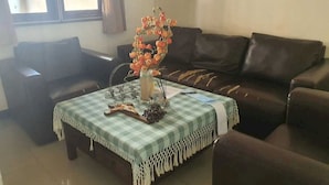 A living room with a checkered tablecloth, a vase with flowers, and a brown leather couch. - OYO Life 93202 Pentagon Homestay Syariah (Surabaya)