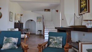 Un vaste salon comprenant un escalier, un coin repas et une cheminée.