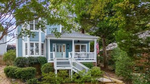 A two-story house with a porch, a small deck, and a wooden staircase leading to the deck.