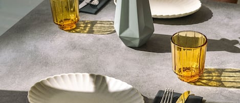 A dining table set with plates, cutlery, and glasses, with a vase of flowers on the table.