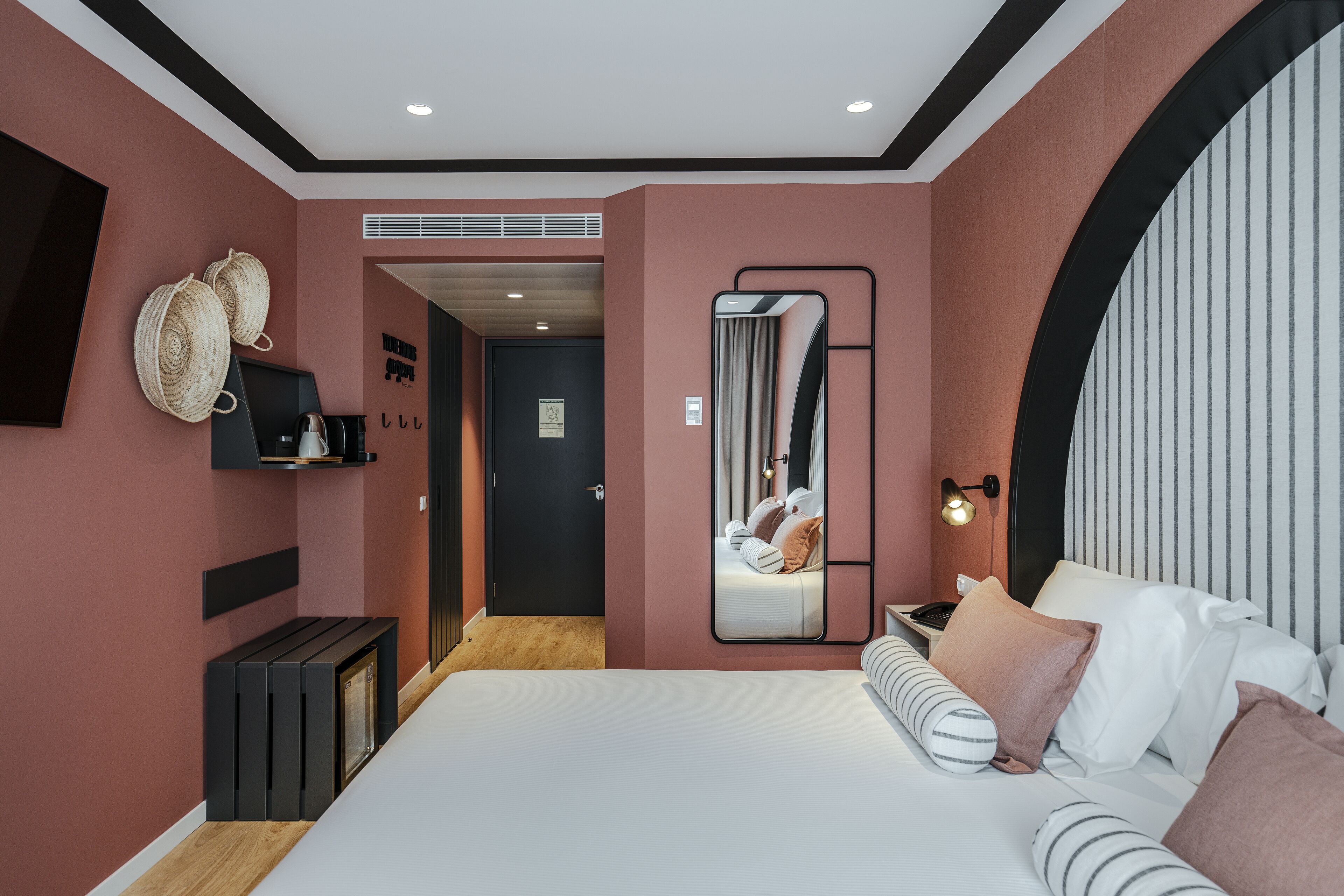 A modern bedroom with a large bed, a mirror, and a small bedside table.