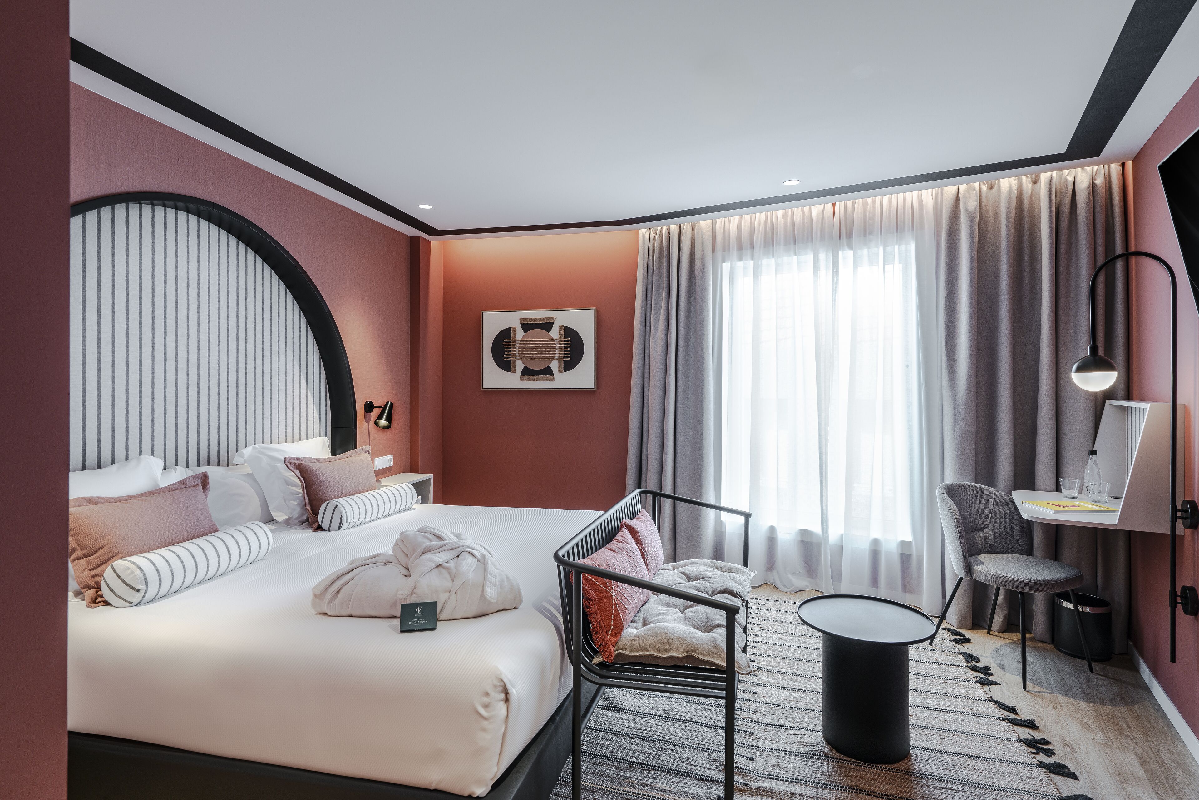 A modern hotel room with a large bed, a desk, and a chair.