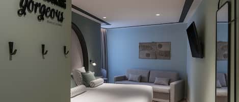 A modern hotel room with a bed, a sofa, a wall-mounted TV, and a decorative mirror.