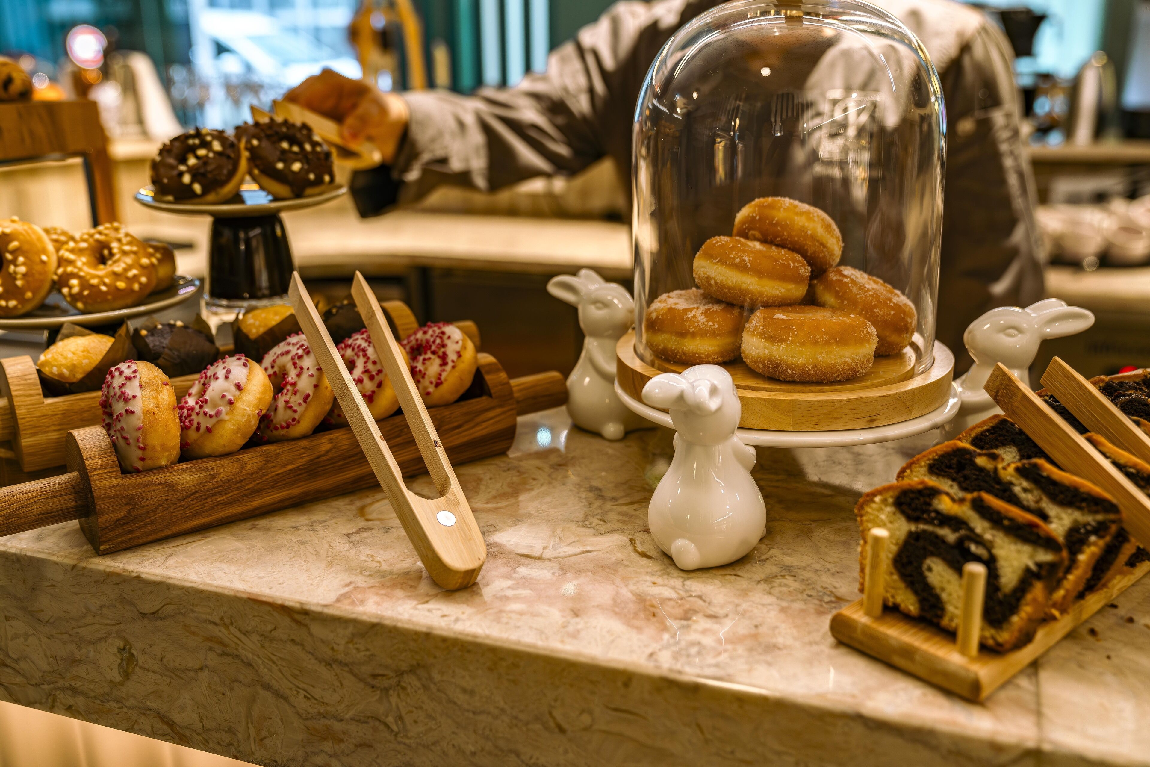 A variety of pastries displayed on a marble countertop, including donuts and cakes.