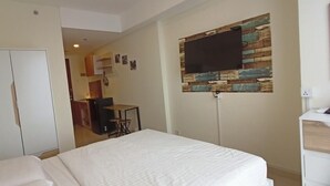 Ein Hotelzimmer mit Bett, Schreibtisch, Stuhl, einem an einer Holzwand montierten Fernseher und einem Kleiderschrank.