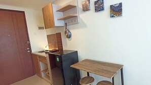Eine kleine Küche mit einem Kühlschrank, einem Spülbecken und einem Holztisch.